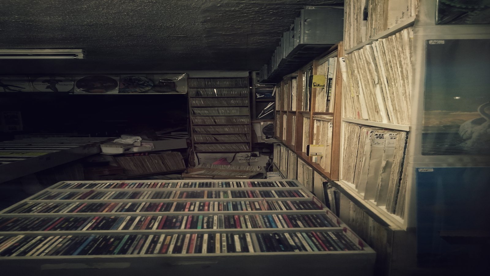 A reading desk with stacked music books, a record sleeve, and a small lamp