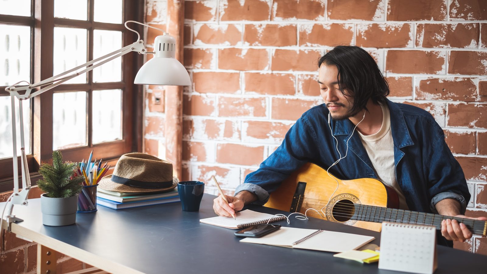 A writing workspace with notebook and acoustic guitar